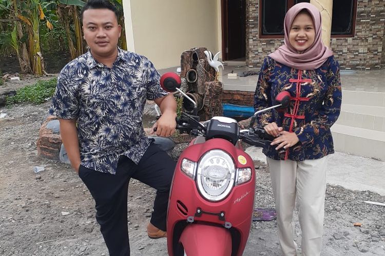 Satria bersama sang istri berfoto dengan sepeda motor yang baru dibelinya menggunakan uang koin seribuan