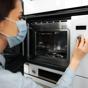 Ilustrasi wanita sedang menggunakan microwave.