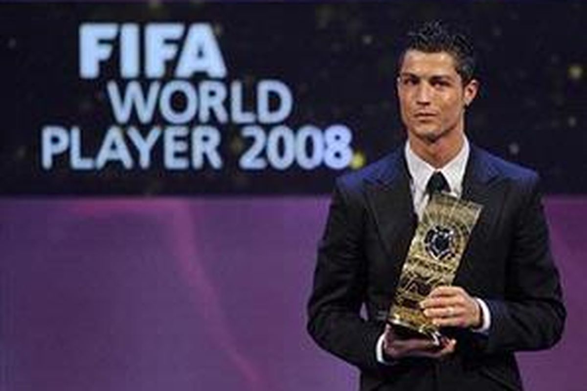 Cristiano Ronaldo tersenyum memegang trofi sebagai Pemain Terbaik Dunia versi FIFA.