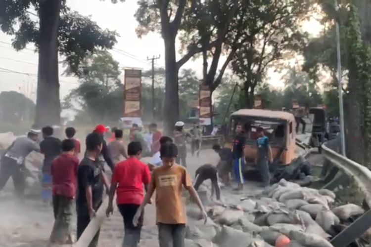 Sejumlah warga berupaya membersihkan badan jalan dari tumpahan semen akibat truk terguling di ruas jalan raya Cugenang, Cianjur, Jawa Barat, Kamis (22/6/2023) petang.