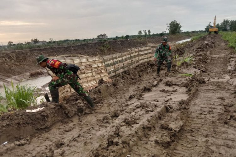 Prajurit TNI dari Kodim 0817 Gresik turut membantu perbaikan tanggul yang jebol, yang menyebabkan dua dusun di Desa Cermen, Kecamatan Kedamean, Gresik, Jawa Timur, terendam banjir.