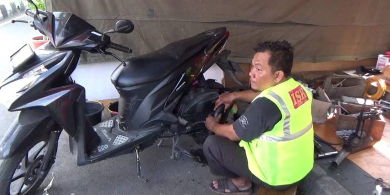 Salah seorang anggota Info Seputar Klaten tengah membantu memperbaiki kendaraan pemudik secara gratis.