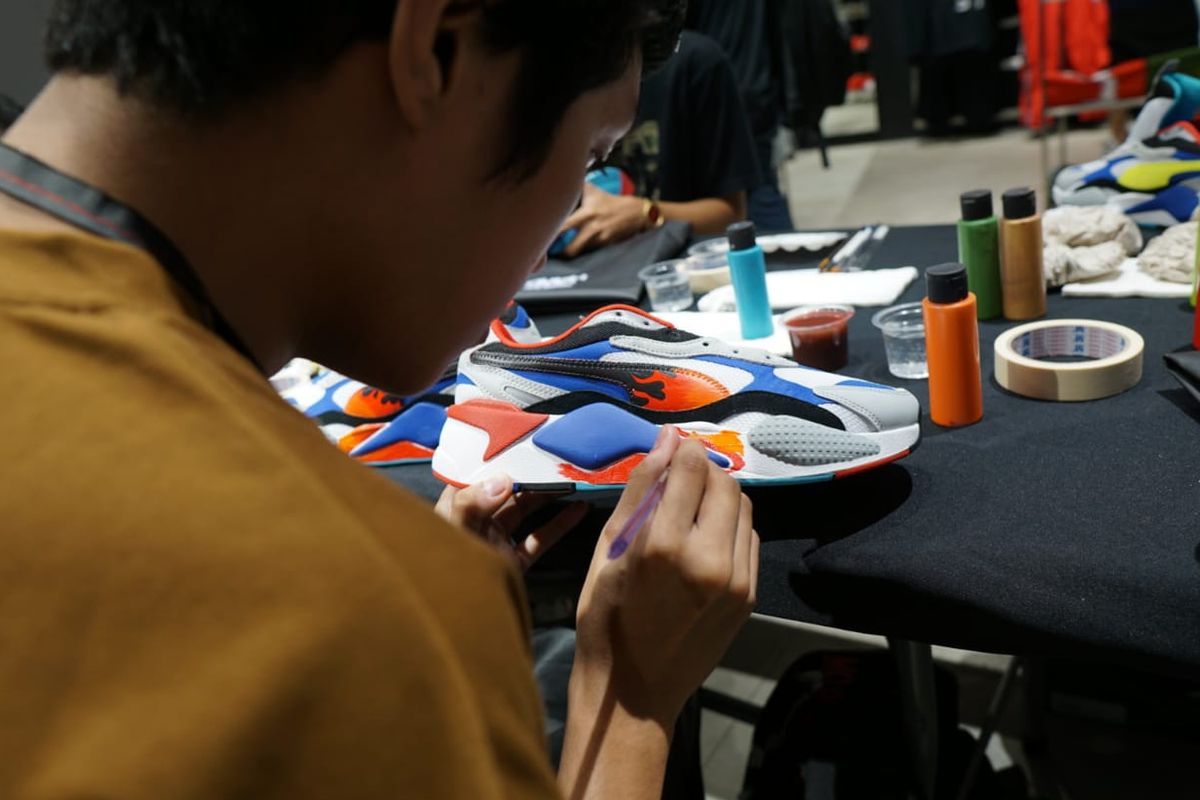 Salah satu peserta workshop customize sneaker Puma RS-X3 di Gerai Puma, Senayan City, sedang berkreasi dengan cat akrilik dan kuas. 