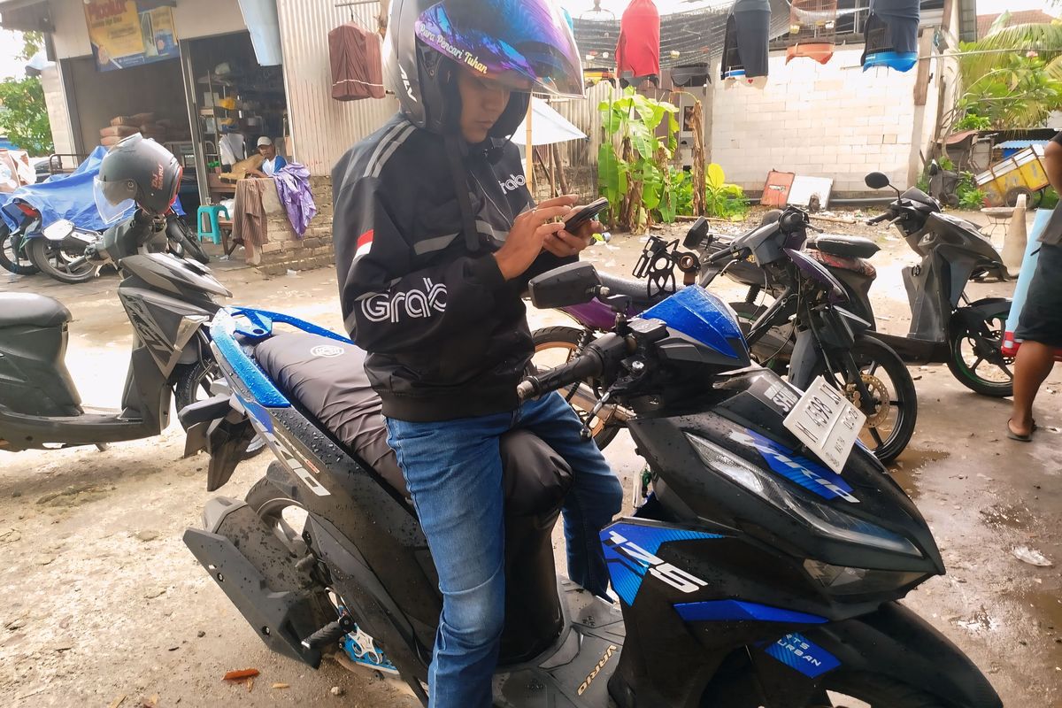 Salah satu pengemudi ojek online, Tegar Putra (36) saat hendak menjemput pelanggannya yang memesan lewat aplikasi, Kabupaten Bangkalan, Jawa Timur, Senin (19/5/2025). 