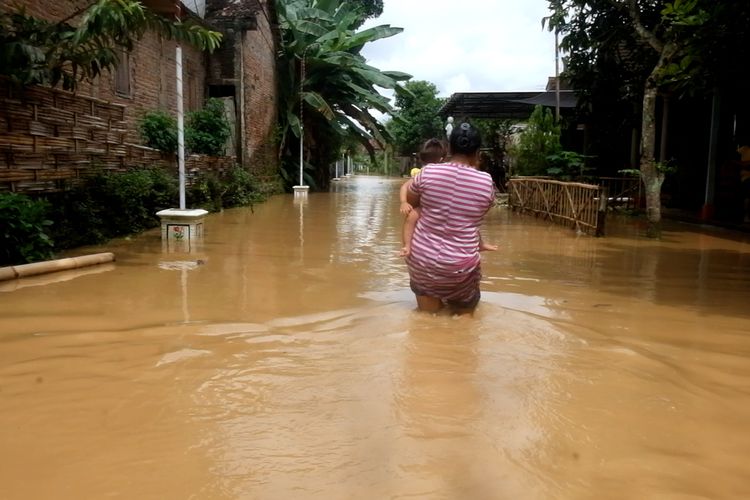 Warga desa Salamrejo Kecamatan Karangan Trenggalek Jawa Timur, melintas di kawasan permukiman yang terendam banjir, Sabtu (08/10/2022).