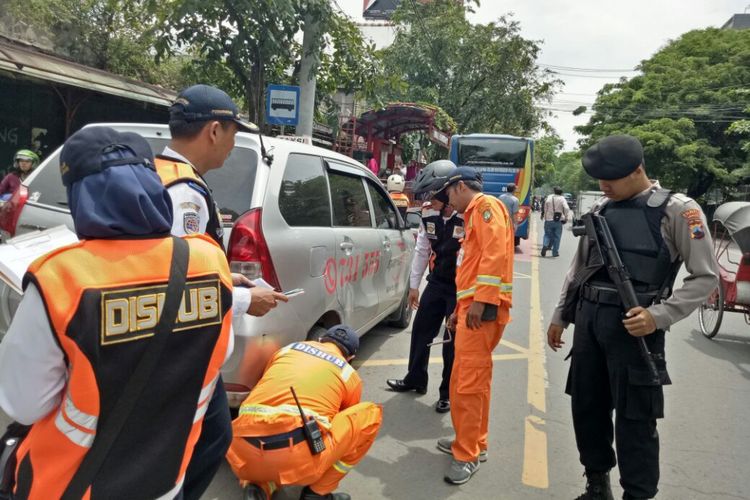 Petugas gabungan menggembok mobil yang terparkir di tempat larangan perkir di Solo, Jawa Tengah, Sabtu (2/12/2017).