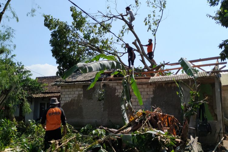 Petugas BPBD bersama masyarakat membersihkan batang pohon yang menimpa rumah di kampung Sukasirna, Desa Lembursawah, Kecamatan Cicantayan, Sukabumi, Jawa Barat, Sabtu (23/2/2019).