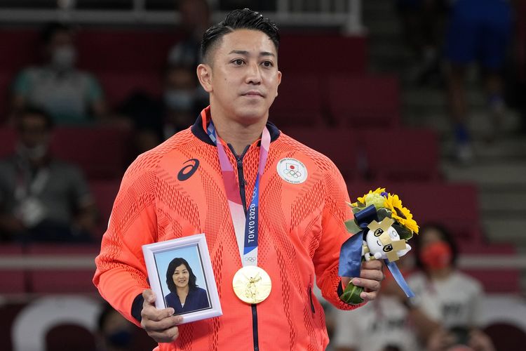 Atlet karate Jepang Ryo Kiyuna membawa foto mendiang ibunya saat upacara pengalungan medali, setelah dia memenangkan emas di nomor kata putra Olimpiade Tokyo, 6 Agustus 2021.