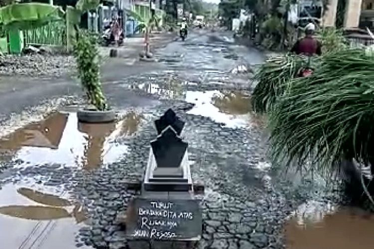 Batu nisan diletakkan warga di pohon pisang yang ditancapkan di jalan rusak menuju pabrik gula PT RMI, Desa Rejoso, Kecamatan Binangun, Kabupaten Blitar, Kamis (18/11/2021)