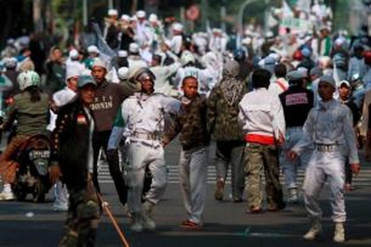 Massa Front Pembela Islam (FPI) melemparkan batu ke arah Gedung DPRD DKI Jakarta saat melakukan aksi unjuk rasa, Jumat (3/10/2014). MAssa FPI berdemo menolak Ahok diangkat menjadi Gubernur DKI Jakarta.