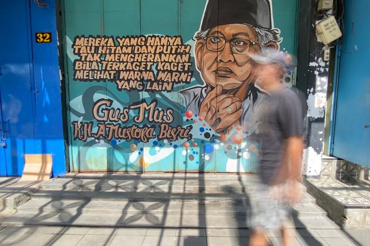 Seorang pengguna jalan melintasi mural bergambar ilustrasi KH A. Mustofa Bisri dan nukilan pemikiran bertema toleransi oleh sosok yang akrab disapa Gus Mus ini di Jl Gatot Subroto, Serengan, Kota Solo, Jawa Tengah, Kamis (8/2/2024. Kota Solo yang selama tiga tahun terakhir menyandang predikat sebagai Kota Toleran menurut lembaga Setara Institute, dikritisi sejumlah kalangan karena dinilai belum inklusif untuk keberagaman gender.