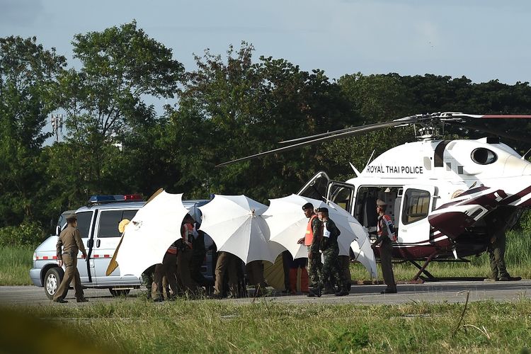 Polisi dan militer Thailand menggunakan payung untuk menutupi helikopter yang membawa salah seorang remaja yang berhasil dikeluarkan dari goa. 12 remaja dan seorang pelatih anggota tim sepak bola Mu Pa (Wild Boar) terjebak di Goa Tham Luang sejak 23 Juni.