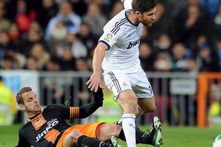 Striker Valencia dari Spanyol, Roberto Soldado (kiri), menekel gelandang Real Madrid berpaspor Spanyol, Xabi Alonso, dalam laga perempat final Copa del Rey di Stadion Santiago Bernabeu, Selasa (15/1/2013). 