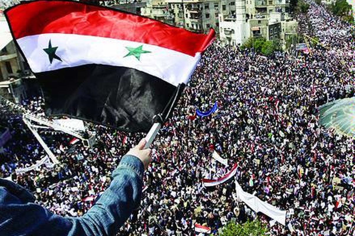 Seorang pengunjuk rasa pro-Presiden Suriah Bashar al-Assad melambaikan bendera Suriah kepada massa pendukung presiden di Damaskus, Suriah, Selasa (29/3). Para pendukung Assad bernyanyi-nyanyi dan melambaikan gambar sang presiden, yang tengah mendapat guncangan terberat dalam 11 tahun berkuasa.