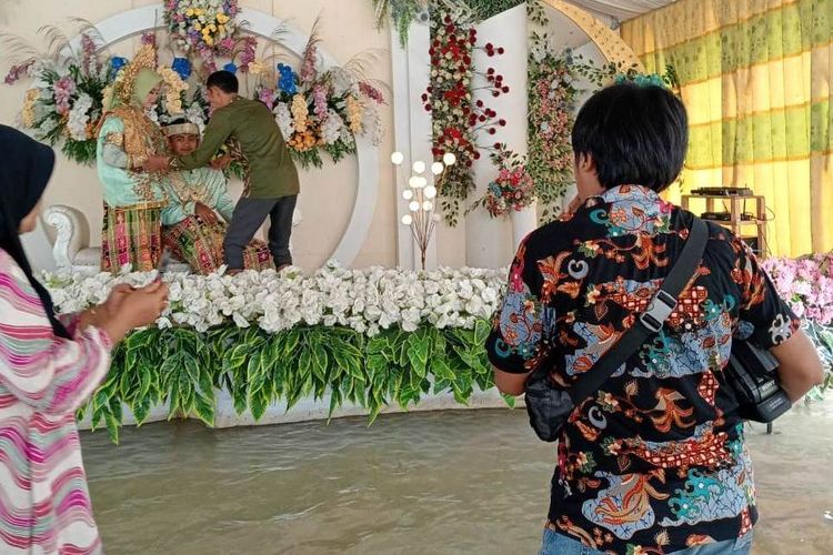 Meski banjir, pasangan pengantin di Dusun Kaluku Bulawang, Desa Lembang-lembang, Luwu Utara, Sulawesi Selatan, Rabu (24/4/2024) siang, tetap gelar resepsi pernikahan di tengah banjir