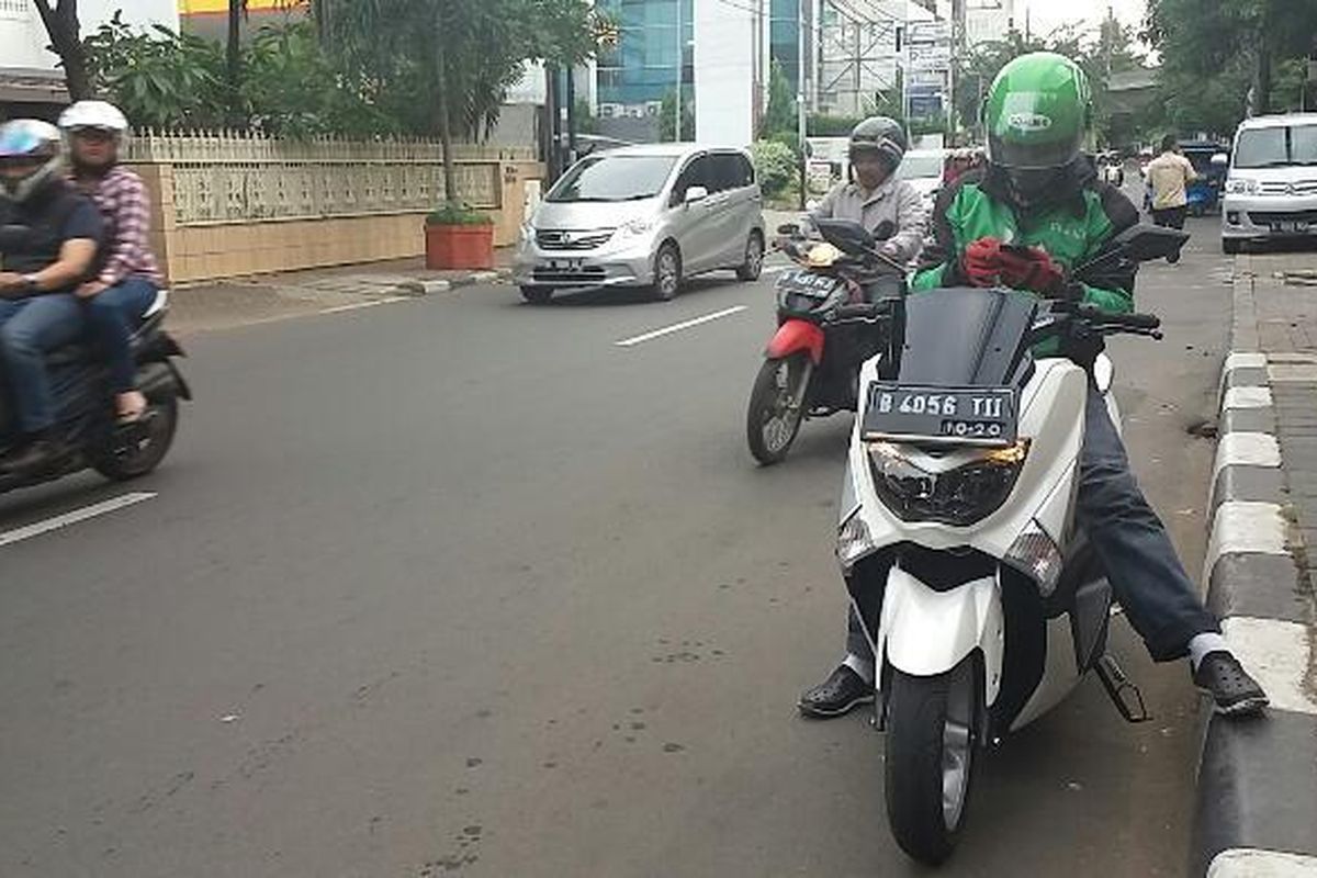 Pengendara ojek online, Hermawan (30) yang menggunakan motor Yamaha NMAX saat berada dikawasan Cikini, Jakarta Pusat pada Minggu (27/12/2015). Motor jenis itu jarang digunakan oleh kebanyakan pengojek, sebab harganya mencapai dua puluhan juta.