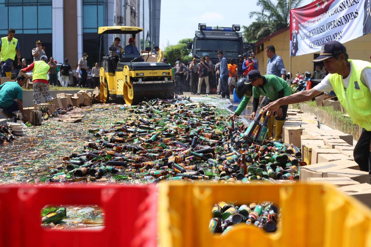Petugas kepolisian memusnahkan 6.000 botol minuman keras (miras) di Halaman Gedung Polres Tangerang Selatan, Jumat (13/4/2018). Polres Tangerang Selatan mengungkap hasil penangkapan 5 orang tersangka yang terlibat dalam pembuatan dan peredaran miras oplosan.