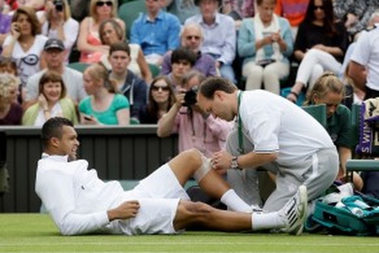 Petenis Perancis, Jo-Wilfried Tsonga, terbaring di lapangan saat mendapat perawatan dari tim medis karena cedera lutut, ketika menghadapi petenis Latvia, Ernests Gulbis, pada babak kedua turnamen grand slam Wimbledon, Rabu (26/6/2013).