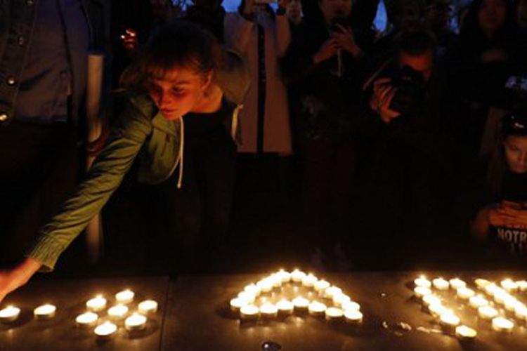 Seorang perempuan menyalakan lilin dalam aksi unjuk rasa menyusul tewasnya seorang lelaki keturunan China di Paris, akinat tembakan polisi Minggu lalu. Aksi ini digelar pada Kamis malam (30/3/2017) waktu setempat.  