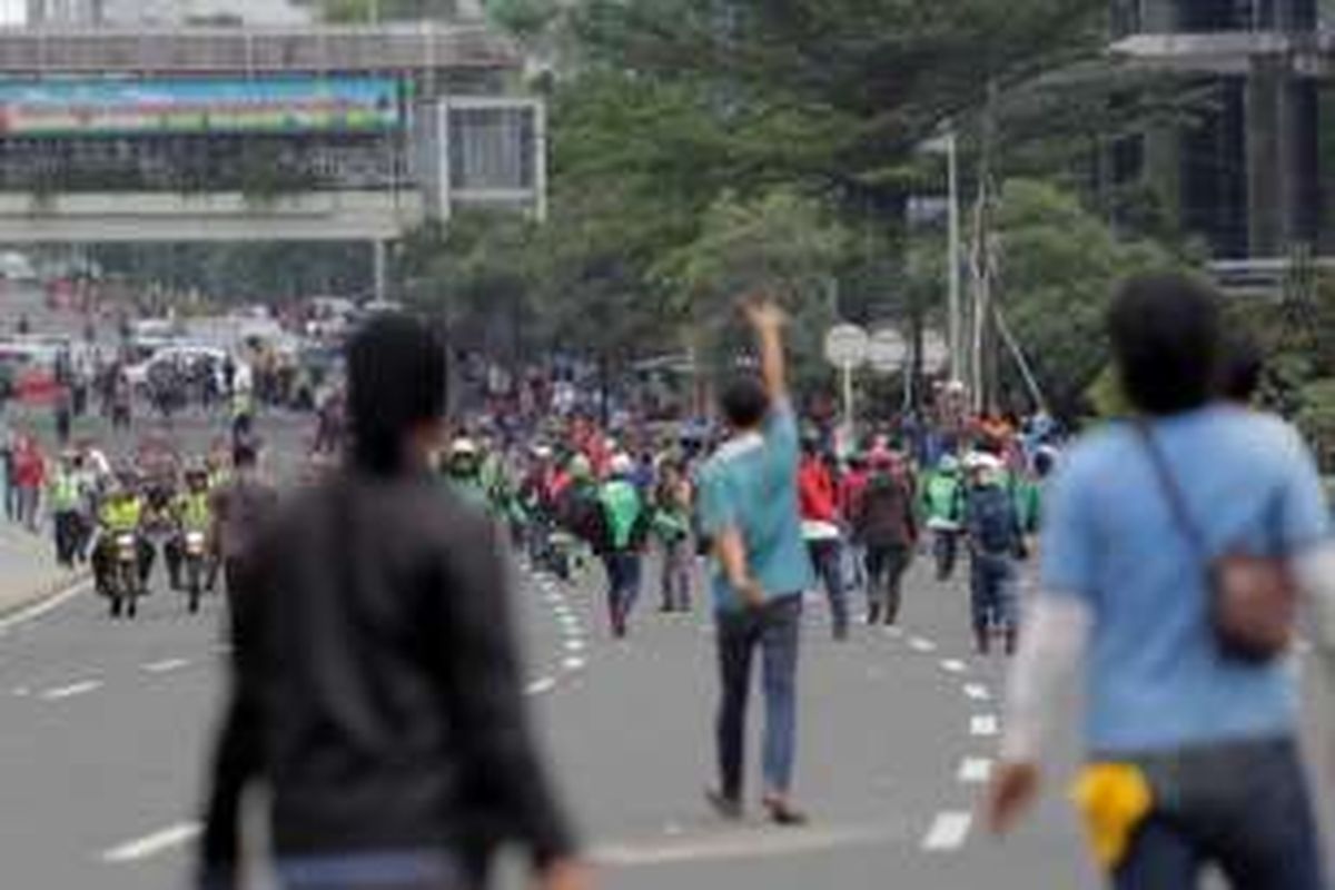 Sejumlah pengemudi ojek online terlibat aksi saling lempar batu dengan para sopir taksi yang berdemonstrasi di Jalan Sudirman, Jakarta, Selasa (22/3/2016). Aksi ini dipicu karena salah satu pengemudi ojek online disweeping oleh para demonstran.