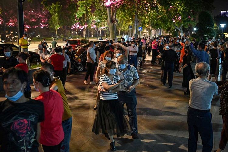 Sejumlah pasangan dengan mengenakan masker menari di sebuah taman di sebelah Sungai Yangtze, Wuhan, Provinsi Hubei, China, Selasa (12/5/2020). Memasuki enam pekan bebas dari lockdown yang diterapkan akibat pandemi Covid-19 sejak Januari lalu, warga Wuhan kembali beraktivitas walau dalam kondisi terbatas.