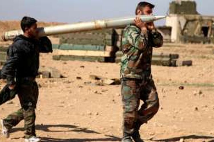 Dua orang prajurit AD Suriah mengangkut sebuah roket yang digunakan untuk menembak posisi ISIS di kota Raqqa.