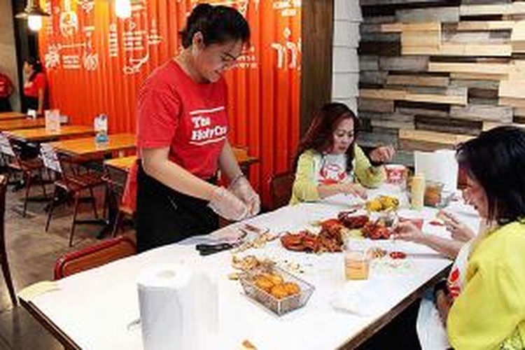 Pramusaji membantu mengupas kepiting di Restoran The Holy Crab di kawasan Kebayoran Baru, Jakarta Selatan.