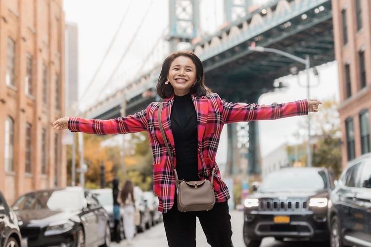 Rossa memadukan turtle neck dan celana hitam dengan blazer plaid merah yang statement dari Kate Spade New York.