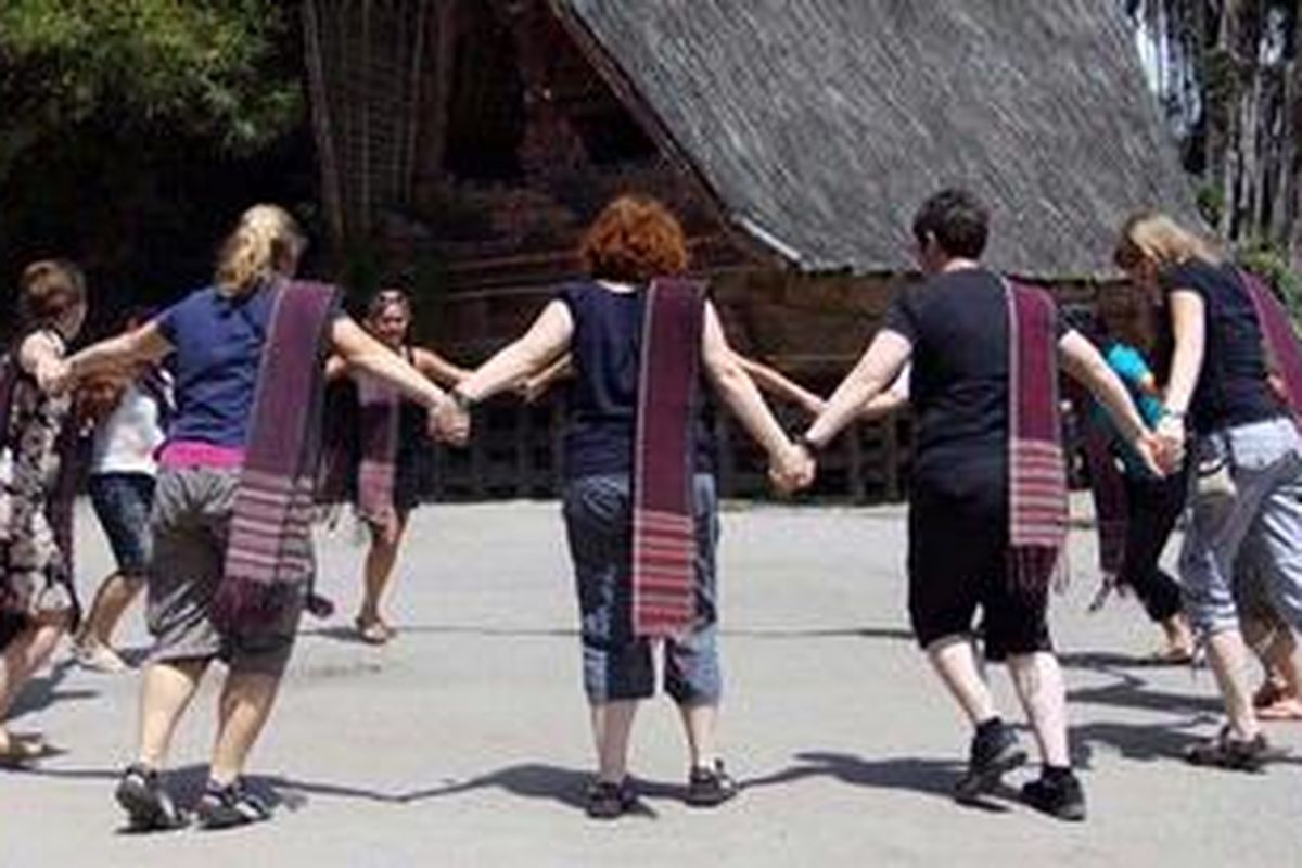 Turis asing turut menari dan mengenakan ulos dalam pementasan di Museum Hutabolon Simanindo di Kecamatan Simanindo, Kabupaten Samosir, Jumat (22/10/2010). Pemerintah Sumatera Utara berusaha meningkatkan kunjungan turis, salah satunya dengan menggelar Pesta Danau Toba 2010 yang berlangsung pada 20-24 November 2010. 