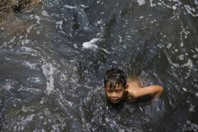 Seorang bocah mandi di Sungai Cikijing yang tercemar dengan limbah industri tekstil di Rancaekek, Bandung, yang airnya mengalir ke Sungai Citarum, 22 Maret 2015.