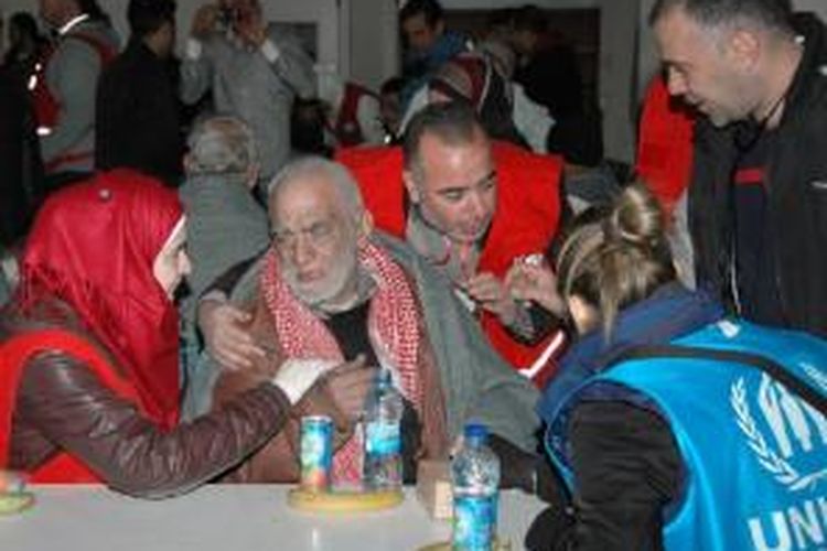 Foto yang dirilis Kantor Berita Suriah SANA memperlihatkan seorang laki-laki lanjut usia menerima makanan dari petugas Bulan Sabit Merah Suriah usai dievakuasi dari Kota Homs, Jumat (7/2/2014).