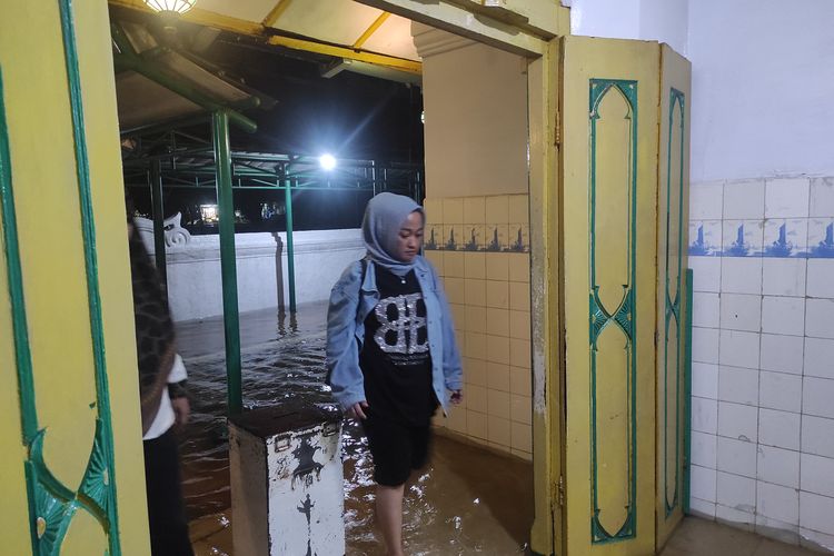 Peziarah memasuki pintu makam Sunan Kalijaga Demak, meski kawasan tersebut terendam banjir, Kamis (14/3/2024) malam. 
