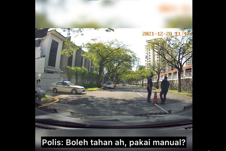 Tangkapan layar video polisi Malaysia menanyai pengendara mobil manual, Kakimu tidak kram?