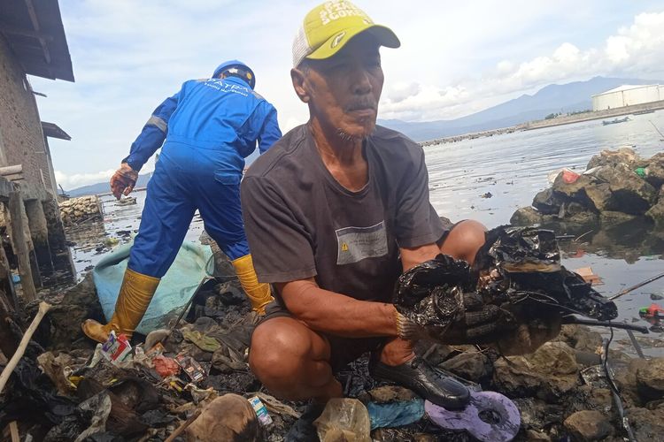 Salah satu warga setempat ikut membersihkan pesisir Bandar Lampung dari limbah hitam diduga oli ataupun minyak.