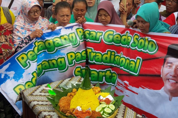 Para pedagang Pasar Gede Solo menggelar tumpengan nasi kuning untuk mendoakan pasangan calon presiden dan wakil presiden nomor urut 01 Jokowi-Maruf Amin di Solo, Jawa Tengah, Kamis (14/2/2019). 