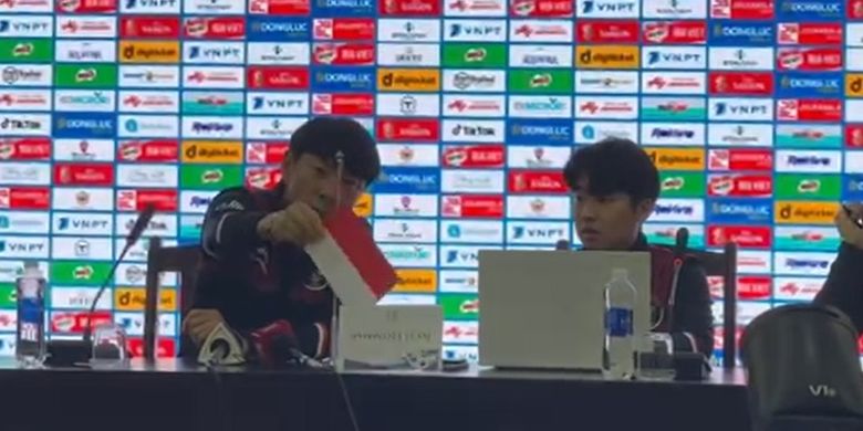 Pelatih timnas U23 Indonesia Shin Tae-yong tampak sibuk membetulkan bendera Indonesia pada sesi konferensi pers menjelang perebutan medali perunggu SEA Games 2021 kontra Malaysia, Sabtu (21/5/2022).