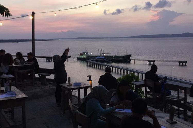 Wisatawan menikmati panorama matahari terbenam di Tebing Kafe & Bar di Kecamatan Alak, Kota Kupang, Nusa Tenggara Timur, Minggu (9/12/2018). Pemandangan matahari terbenam yang dilengkapi dengan lanskap Pelabuhan Tenau bisa jadi salah satu pilihan tempat untuk menikmati matahari terbenam.