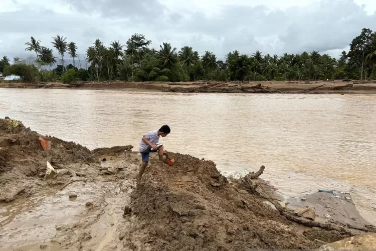 Seorang anak bermain di pinggir Sungai Batang Kuranji yang mengalami pelebaran setelah banjir bandang dan longsor di Kota Padang, Sumatera Barat, Selasa (9/12/2025).