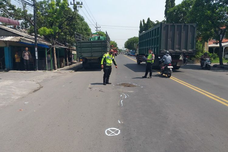 Polisi menunjukkan tempat pasutri berboncengan sepeda motor tertabrak truk tronton di Jalan Raya Desa Sukomulyo, Kecamatan Manyar, Gresik, Jawa Timur, Rabu (20/12/2023).