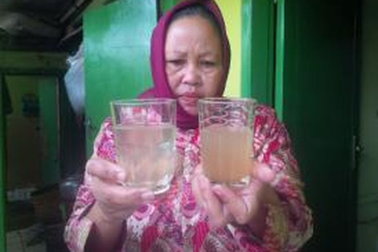 Ernawati Waer (59), warga Kampung Ciwalengke, Desa Sukamaju, Kecamatan Majalaya, Kabupaten Bandung, Jawa Barat, memperlihatkan air selokan (kanan) dan air hasil penyaringan di sumur resapan yang biasa dipakai warga desanya. 