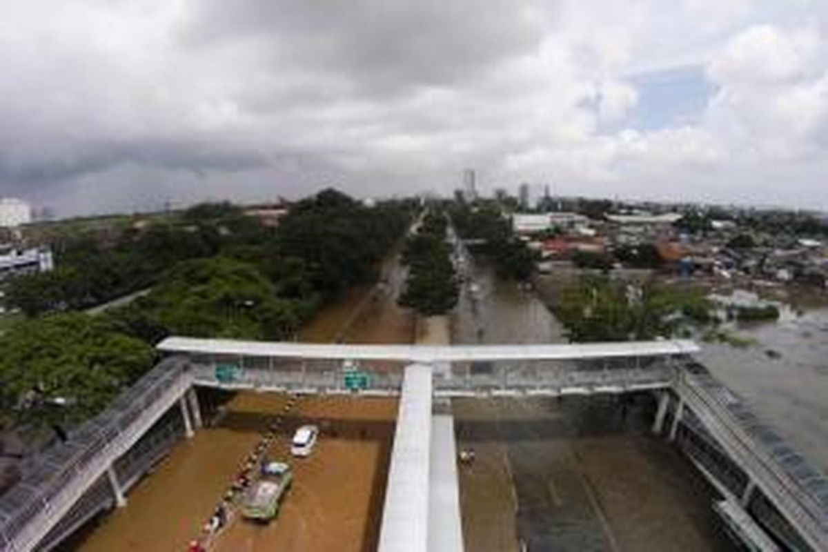 Banjir menggenangi Jalan Perintis Kemerdekaan, Pedongkelan, Jakarta Timur, Selasa (10/2/2015). Jakarta menghadapi masalah penurunan muka tanah. Kondisi itu diperparah oleh semakin minimnya daerah resapan air yang diganti dengan hunian dan gedung-gedung pencakar langit.