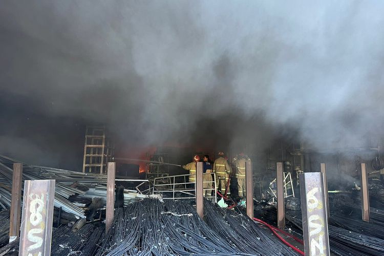 Petugas saat memadamkan api yang membakar toko bangunan di Jalan Raya Putat lor, Desa Putat, Kecamatan Menganti, Gresik, Jawa Timur, Kamis (25/1/2024).