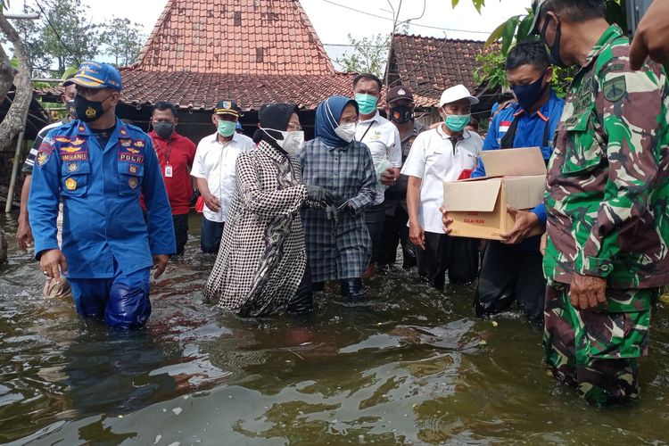 Menteri Sosial Republik Indonesia, Tri Rismaharini, menerobos genangan banjir seusai memberikan bantuan kepada korban banjir di Dukuh Dempel Desa Kalisari Kecamatan Sayung Kabupaten Demak Jawa Tengah yang sudah sepekan ini terendam banjir, Jumat (12/2/2021).