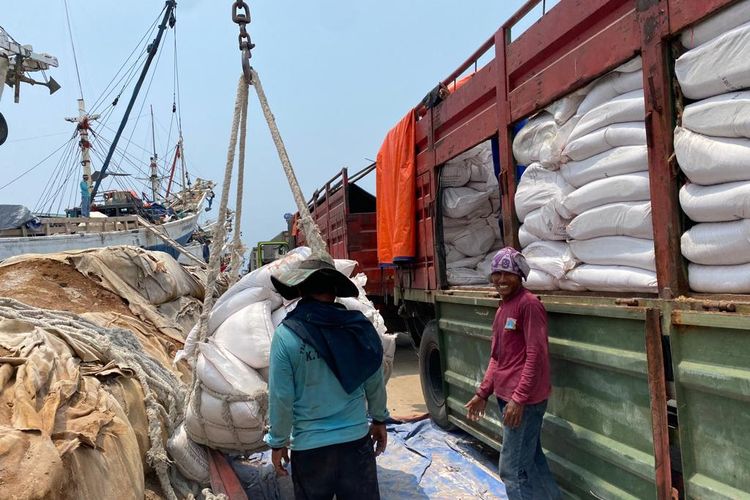 Dua kuli angkut tengah mengangkut muatan dari truk besar di Pelabuhan Sunda Kelapa, Jakarta Utara pada Senin (13/3/2023).