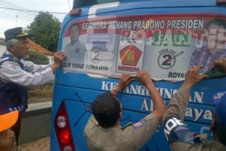 Petugas dari Dinas Perhubungan, dan Satpol PP Brebes, Jawa Tengah mencopot gambar caleg yang menempel di angkutan umum di Jalan Diponegoro, Brebes, Jawa Tengah, Rabu (29/1/2014).