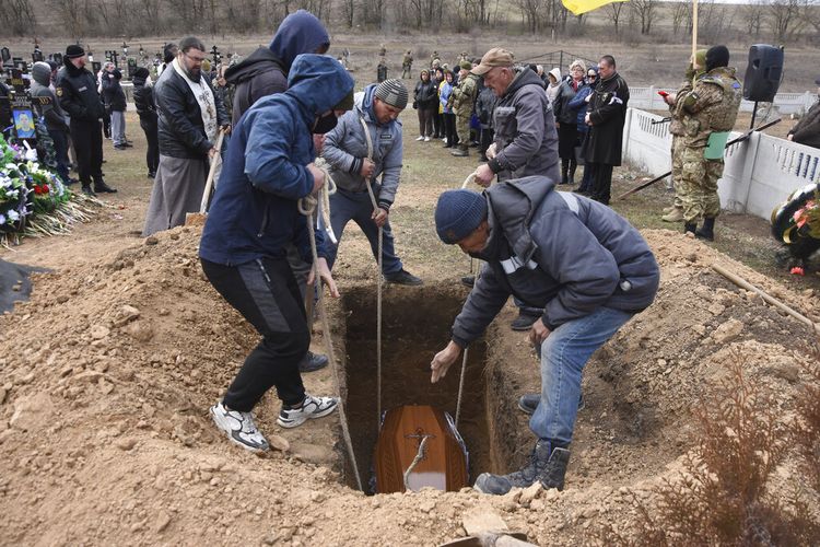 Pria menurunkan peti mati prajurit Ukraina Oleksiy Lunyov ke kuburannya di Yuzhne, wilayah Odessa, Ukraina, Minggu, 27 Maret 2022. 