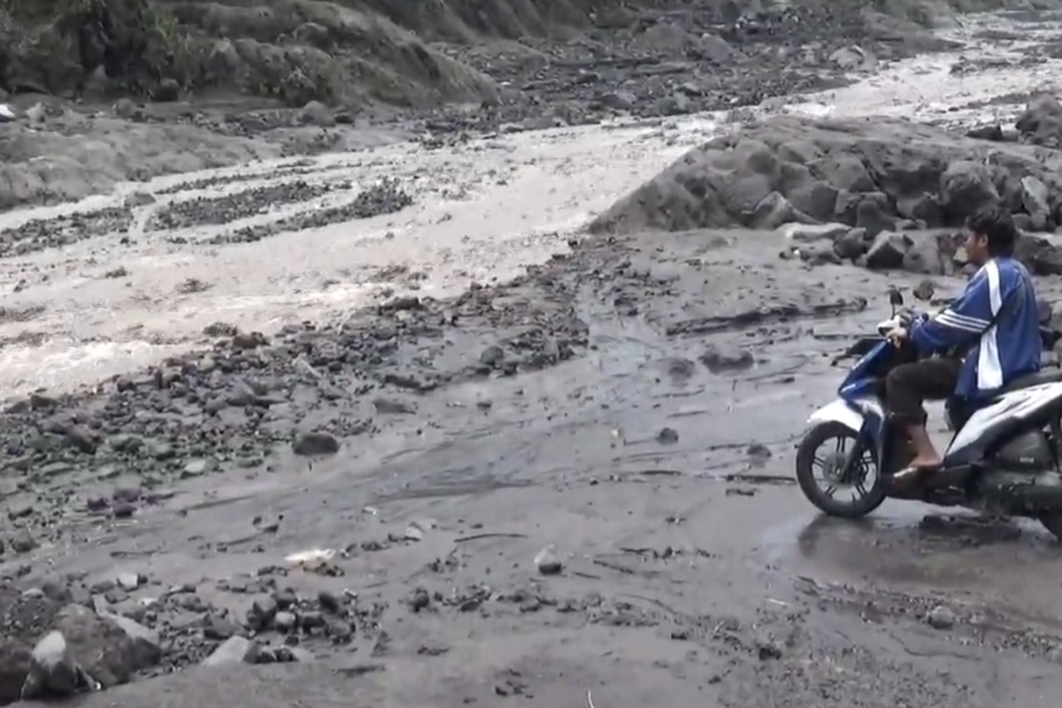 Warga menunggu banjir lahar Gunung Semeru surut di pinggir Sungai Besuk Kobokan agar bisa melintas, Rabu (8/1/2025).