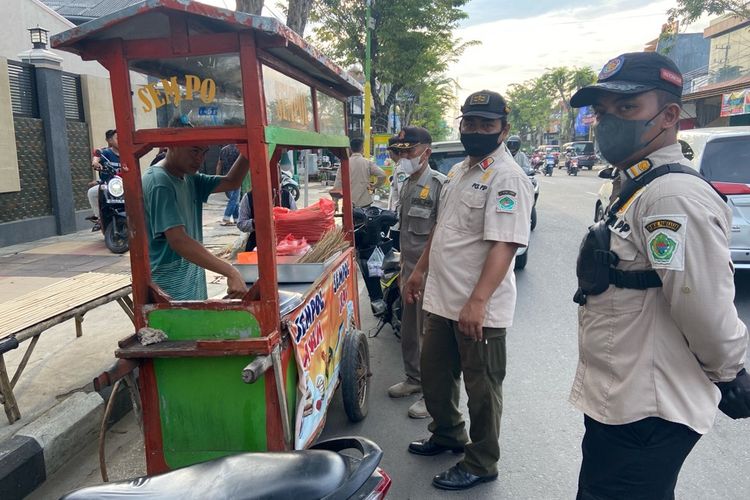Satpol PP Pamekasan menertibkan PKL yang berjualan di sepanjang Jl. Kabupaten yang menempati bahu jalan raya. Para PKL telah membuat kemacetan kendaraan.