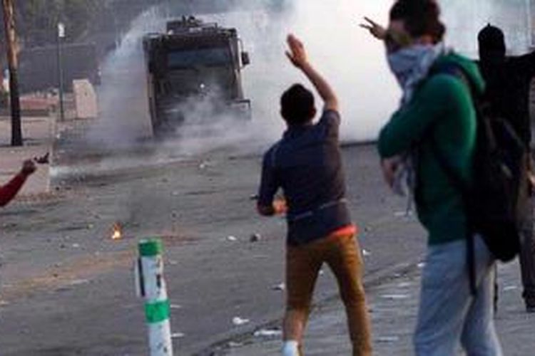 Sejumlah warga Mesir melempari kendaraan lapis baja polisi, di Kairo, Sabtu (9/3/2013) dalam aksi unjuk rasa memprotes keputusan pengadilan Mesir, di Kairo, Sabtu (9/3/2013), berkaitan dengan kerusuhan suporter yang menewaskan 74 orang pada Februari 2012. 
