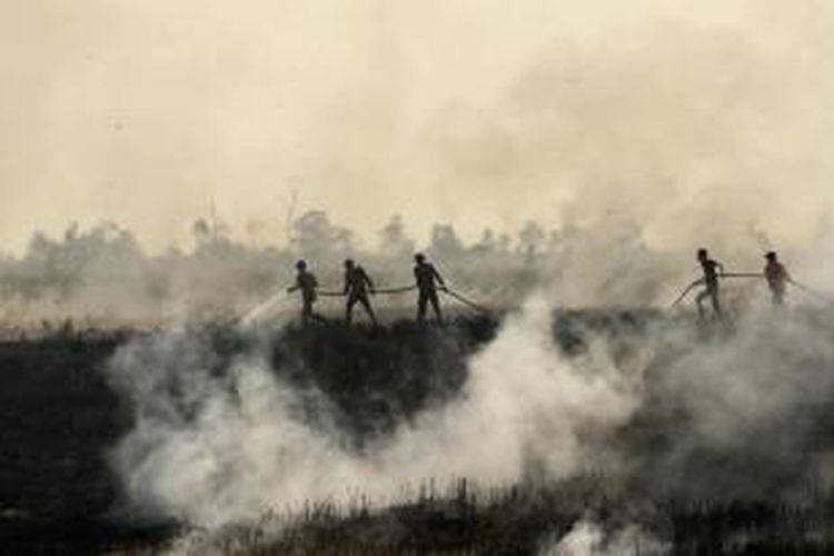 Petugas berupaya memadamkan kebakaran hutan di Ogan Ilir, Sumatera Selatan, 5 September 2015. Kabut asap yang menyelimuti beberapa negara Asia Tenggara disebabkan oleh kebakaran hutan di Indonesia.
